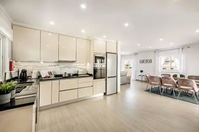 a kitchen with white cabinets and a living room at Villa Simoes in Guia