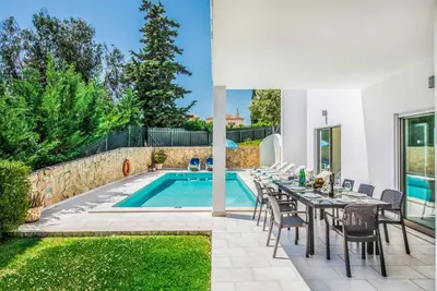 a patio with a table and chairs next to a swimming pool at Villa Sao Joao in Caliços