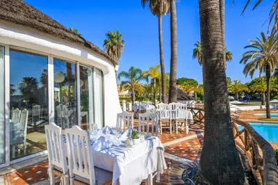 a dining room with a table and chairs next to a pool at Encosta Do Lago Resort Club in Quinta do Lago