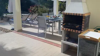 a patio with a table and chairs and an umbrella at Villas Sol e Poesia in Albufeira