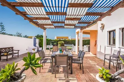 a patio with a table and chairs under a pergola at Villa Charlota in Albufeira
