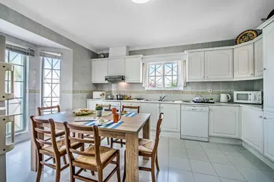 a kitchen with white cabinets and a table and chairs at Villa Arines in Albufeira