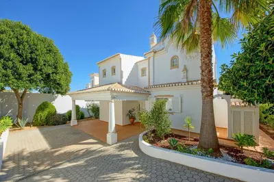a large white house with a palm tree at Villa Adele in Albufeira