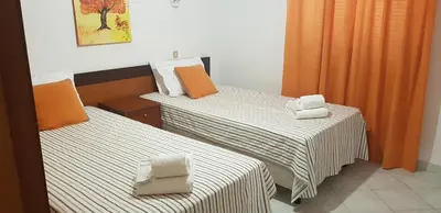 two beds in a hotel room with orange curtains at Villa Brigida in Albufeira