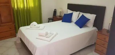 a bedroom with a large white bed with blue and green curtains at Villa Brigida in Albufeira