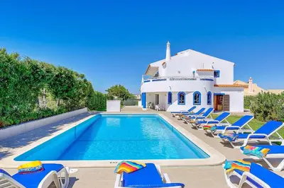 a swimming pool with chairs and a house at Villa Natal in Albufeira
