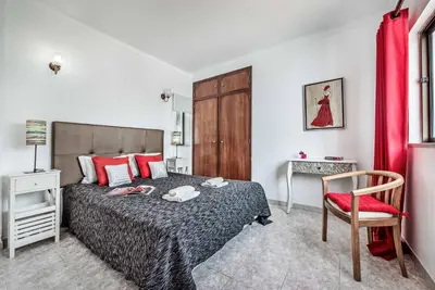 a bedroom with a bed and a chair and a table at Villa Severino in Albufeira