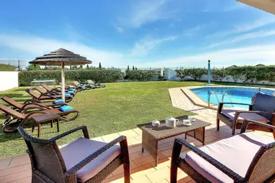 a group of chairs and tables next to a swimming pool at Villa Ceylon in Albufeira
