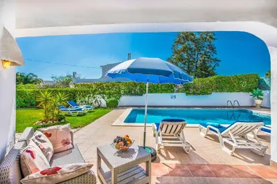 a patio with an umbrella and a swimming pool at Villa Miramar in Albufeira