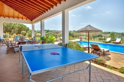 a ping pong table on a patio with a pool at Villa Monte de Madrinha in Albufeira