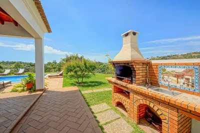 a swimming pool with two chairs and a water fountain at Villa Monte de Madrinha in Albufeira
