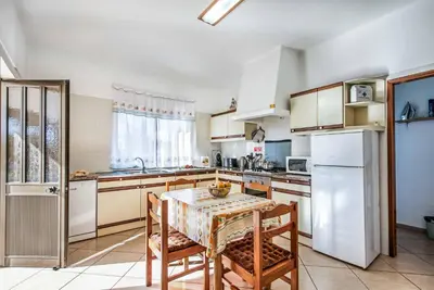 a kitchen with a table and a white refrigerator at Villa Lourenco in Albufeira