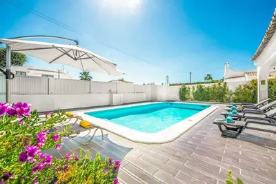a swimming pool with chairs and an umbrella at Casa dos Amigos in Albufeira