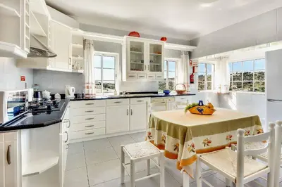a kitchen with white cabinets and a table with chairs at Villa Sunny in Albufeira
