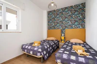 a bedroom with two beds and a wall with a wallpaper at Apartamentos Old Town by Umbral in Albufeira