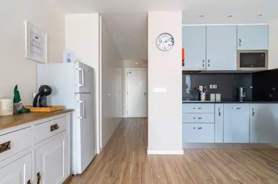 a kitchen with white cabinets and a clock on the wall at CASA JOY Vilamoura apartment in Vilamoura