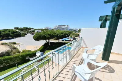 a balcony with two white chairs and a view of a street at TownHouse next to Falésia Beach in Albufeira