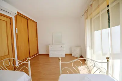 a bedroom with a bed and a dresser and a window at TownHouse next to Falésia Beach in Albufeira