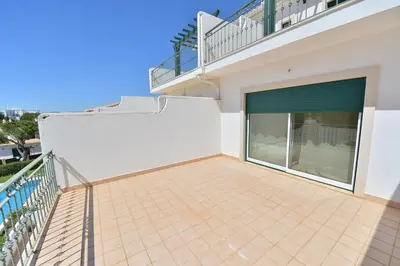 a balcony of a house with a large glass door at TownHouse next to Falésia Beach in Albufeira