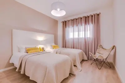 a bedroom with two beds and a chair and a window at Ella - Fantastic apartment - Vilamoura in Vilamoura