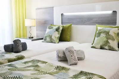 a bedroom with two beds with green and white pillows at Rising Sun Apartment in Albufeira