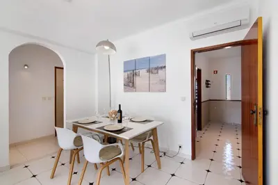 a white dining room with a table and chairs at City Center Albufeira in Albufeira