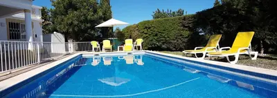 a swimming pool with yellow lawn chairs at Casa Dos Cedros in Guia