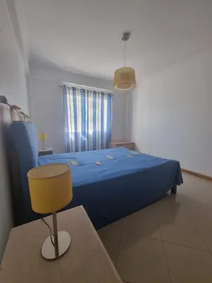 a bedroom with a blue bed with a yellow chair at Albufeira Apart. T2 Baixa in Albufeira
