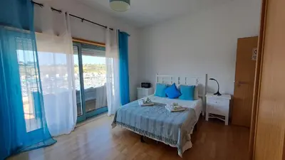 a bedroom with a bed with blue pillows and a window at Albufeira Marina Penthouse 1 in Albufeira