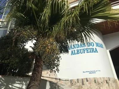 a palm tree in front of a building with a sign at AZUL/MAR ALBUFEIRA 602 in Albufeira
