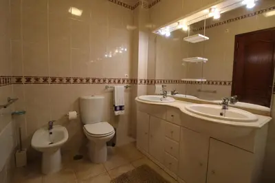 a bathroom with a toilet and a sink and a mirror at Apt T2 Jardins do Castelo - Albufeira, Algarve in Albufeira