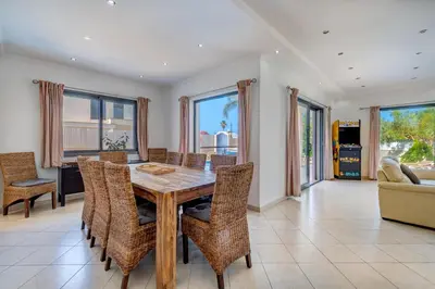 a dining room with a wooden table and chairs at Villa Ruana - 5 bedrooms on Suite- Free out door Hot Jacuzzi - By Bedzy in Albufeira