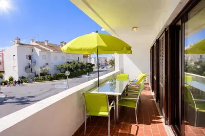 a table with yellow chairs and an umbrella on a balcony at Medronheira by Check-in Portugal in Albufeira