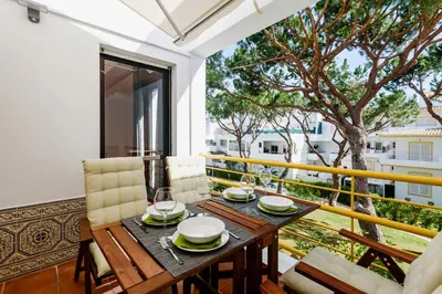 a dining table and chairs on a balcony with a tree at Aldeia das Açoteias Apartment in Roja- Pé