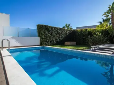 a swimming pool in a yard next to a hedge at Harmony 4F House - Privat Heated Pool & Privacy & Albufeira in Albufeira