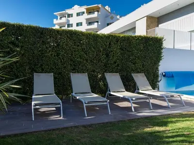 four lounge chairs are lined up next to a hedge at Harmony 4F House - Privat Heated Pool & Privacy & Albufeira in Albufeira