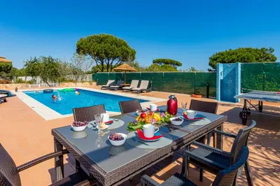 a table with food on it next to a swimming pool at Villa Carlivo in Albufeira