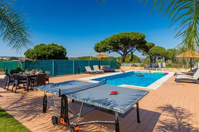 a ping pong table in a backyard with a pool at Villa Carlivo in Albufeira