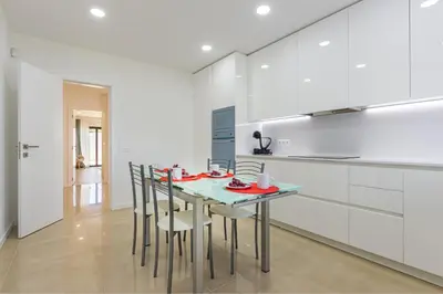 a kitchen with white cabinets and a table with chairs at Villa Casinha in Albufeira