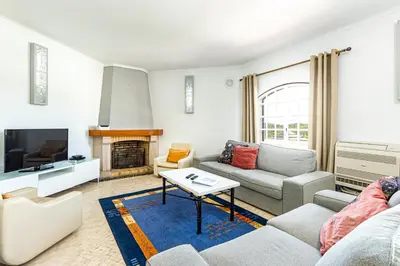 a living room with a couch and a tv at Villa Solar das Palmeiras in Albufeira