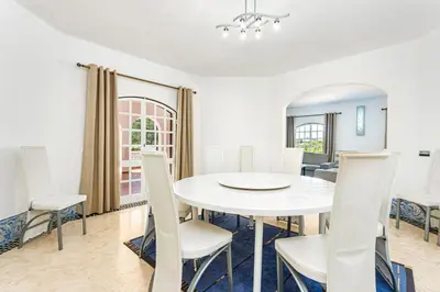 a white dining room with a white table and chairs at Villa Solar das Palmeiras in Albufeira