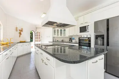 a kitchen with white cabinets and a black counter top at Villa Solar das Palmeiras in Albufeira