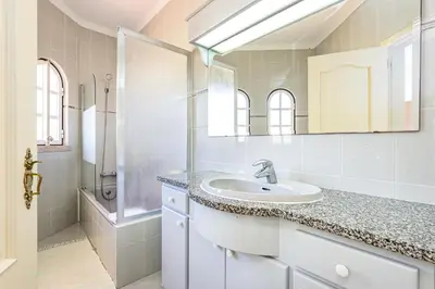 a white bathroom with a sink and a shower at Villa Solar das Palmeiras in Albufeira