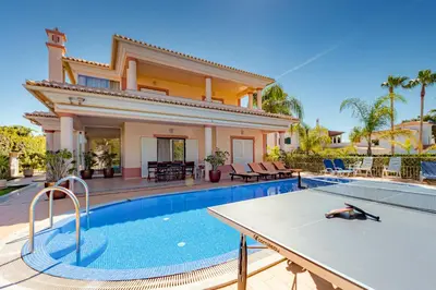 a villa with a swimming pool in front of a house at Villa Cor de Rosa in Albufeira