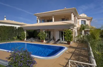 a villa with a swimming pool in front of a house at Villa Cor de Rosa in Albufeira
