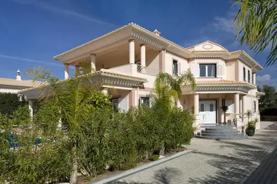 a large pink house with trees in front of it at Villa Cor de Rosa in Albufeira