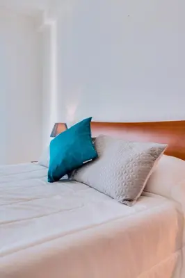 a bed with blue and white pillows on it at Rei - Quarteira - 3 min to the beach in Vilamoura