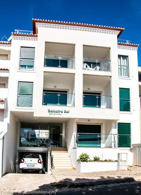 a white building with a car parked in front of it at Apt Baleeira Sol in Albufeira