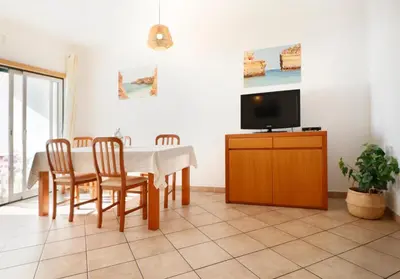 a dining room with a table and chairs and a tv at Apt Baleeira Sol in Albufeira