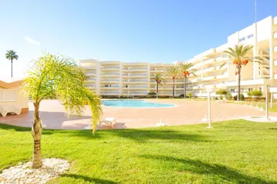 a palm tree in front of a large building at Galé Mar by OCvillas in Galé